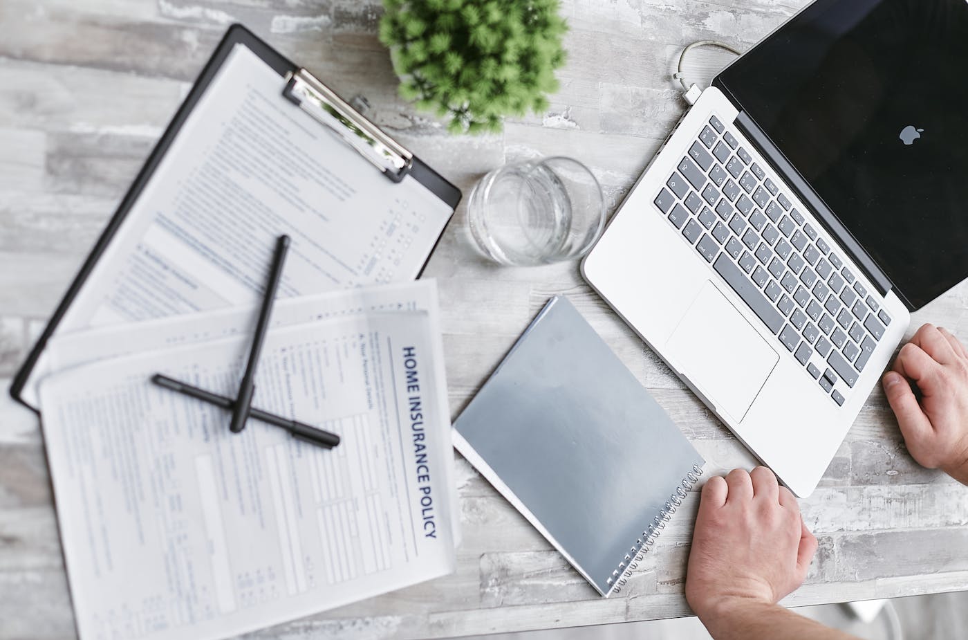 Hands taking notes at a desk with a laptop and coffee