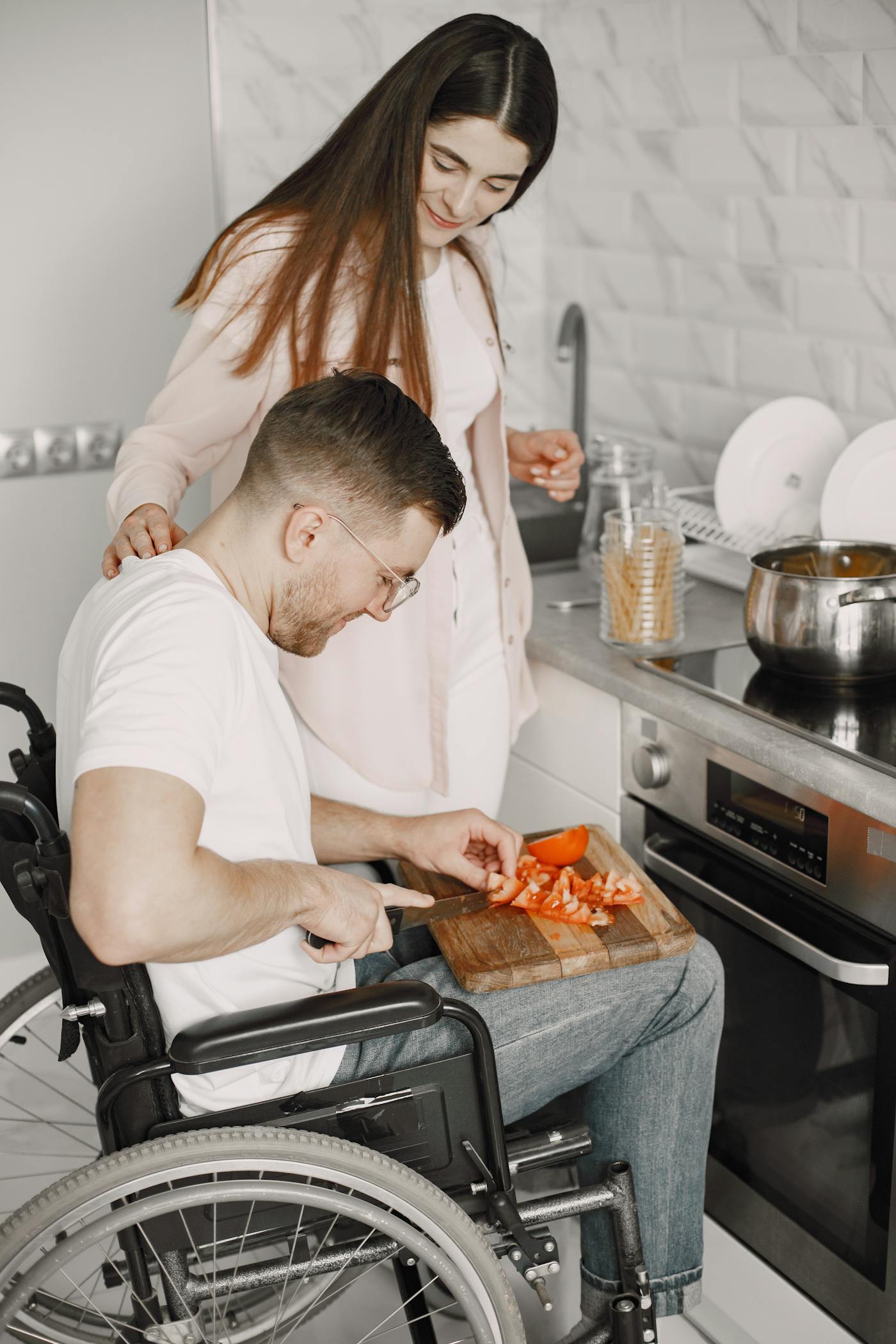 A caregiver helping someone prepare food in a home kitchen